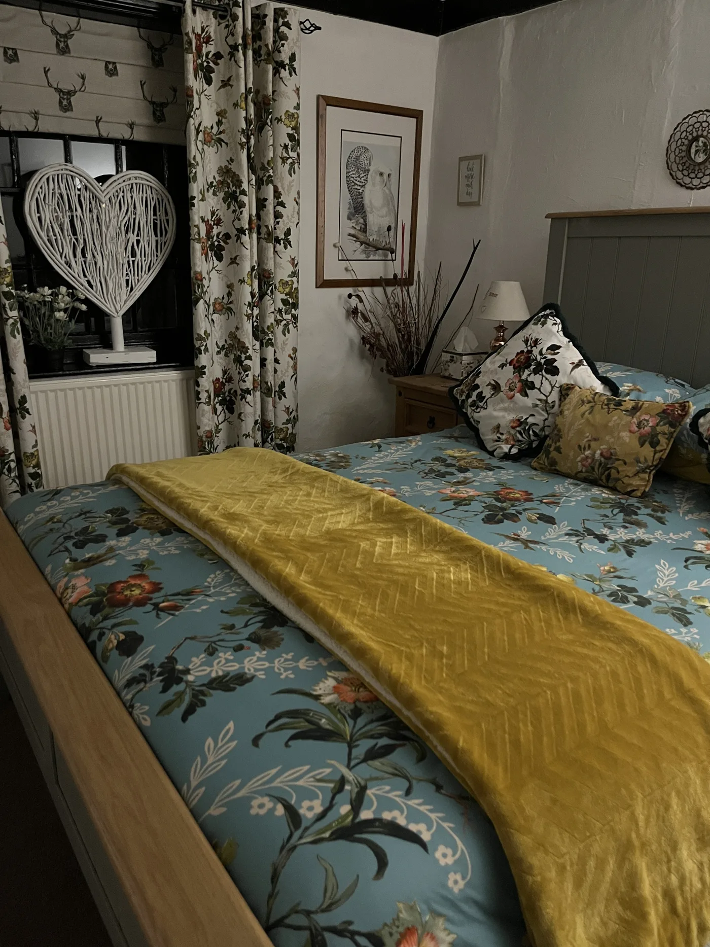 Bedroom with blue floral bedding, golden quilted throw and beamed ceiling at The Blue Boar Inn