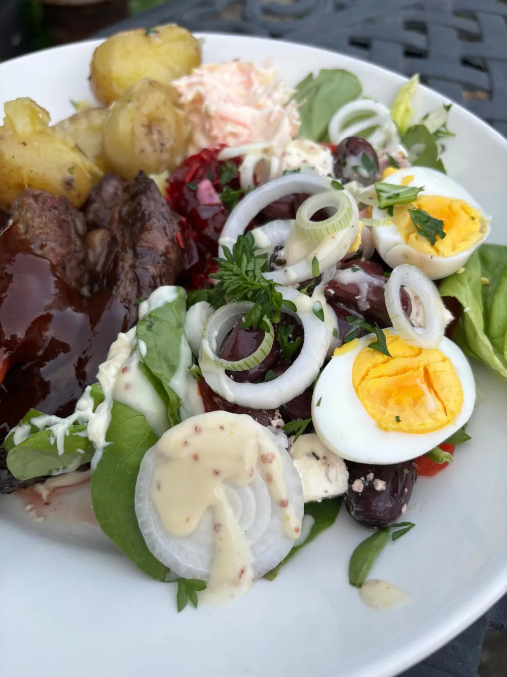 A steak salad with new potatoes, egg and fresh leaves served in the garden